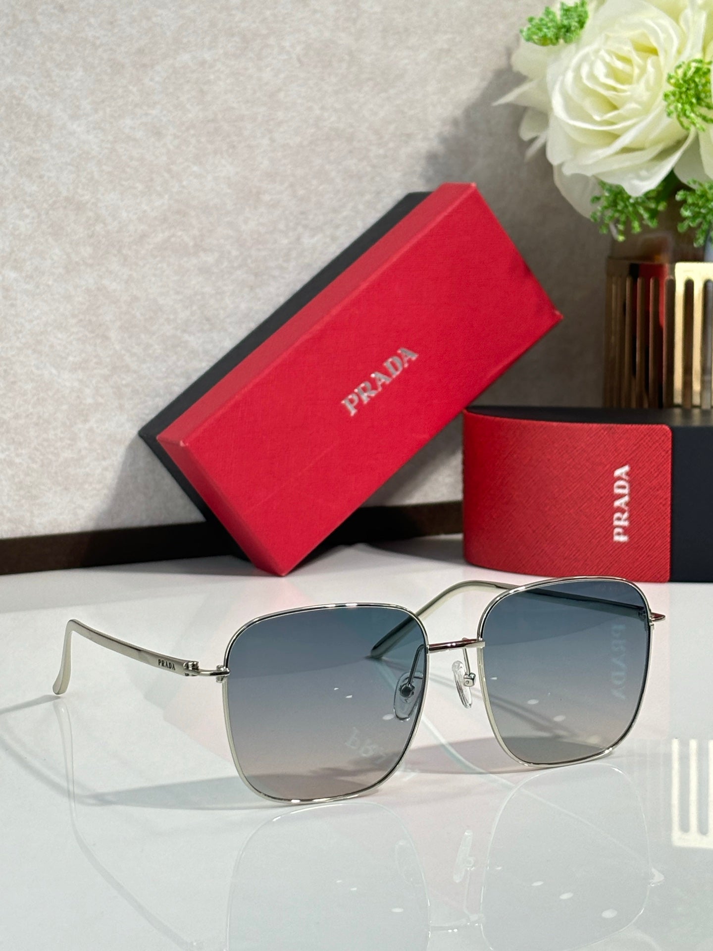 Prada sunglasses with silver frame and blue-gray gradient lenses, rectangular aviator style