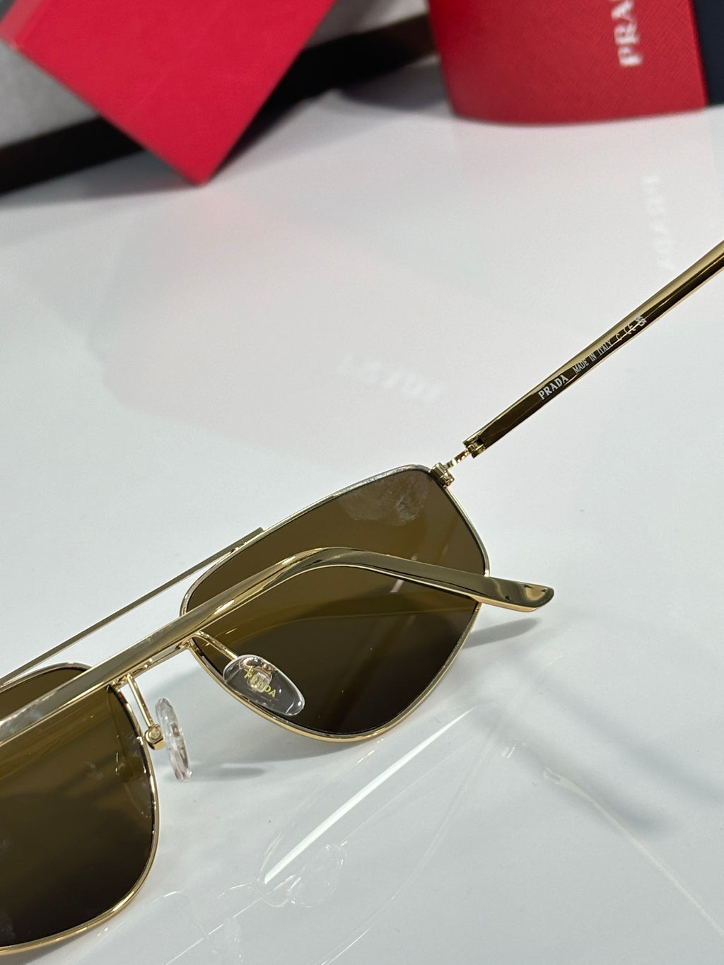 Prada aviator sunglasses close-up, gold temple with logo and tinted lens
