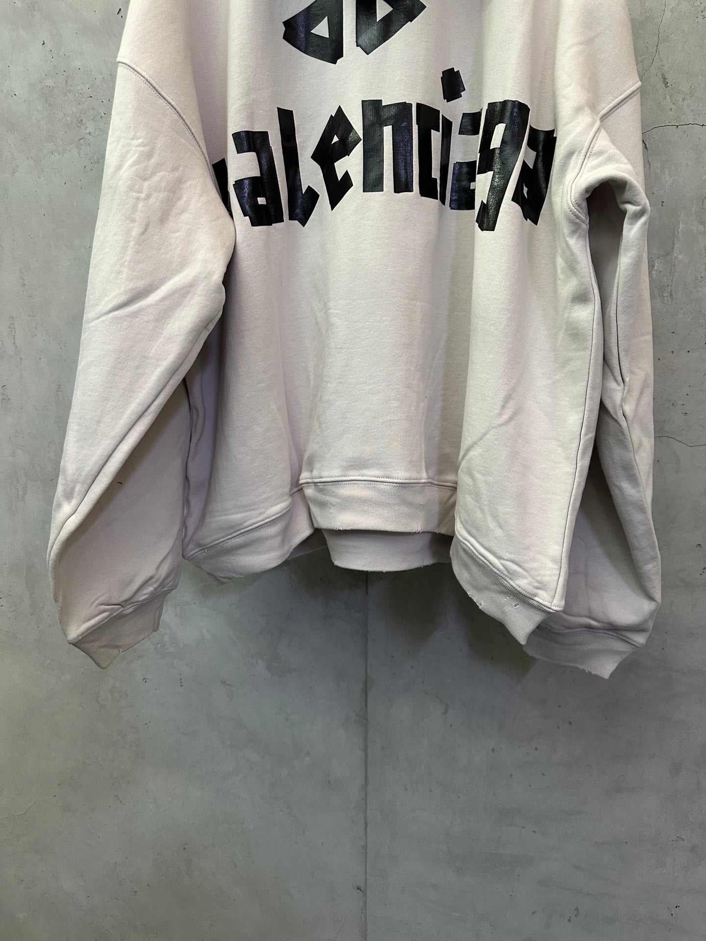 White hoodie with black Balenciaga graphic across the upper back