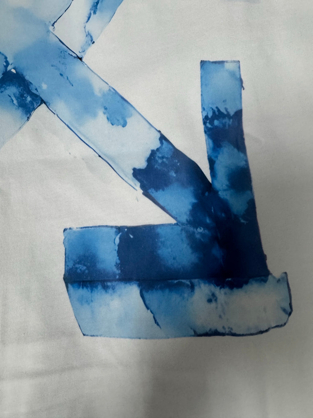 Off-White T-shirt close-up of blue “X” graphic with distressed paint effect