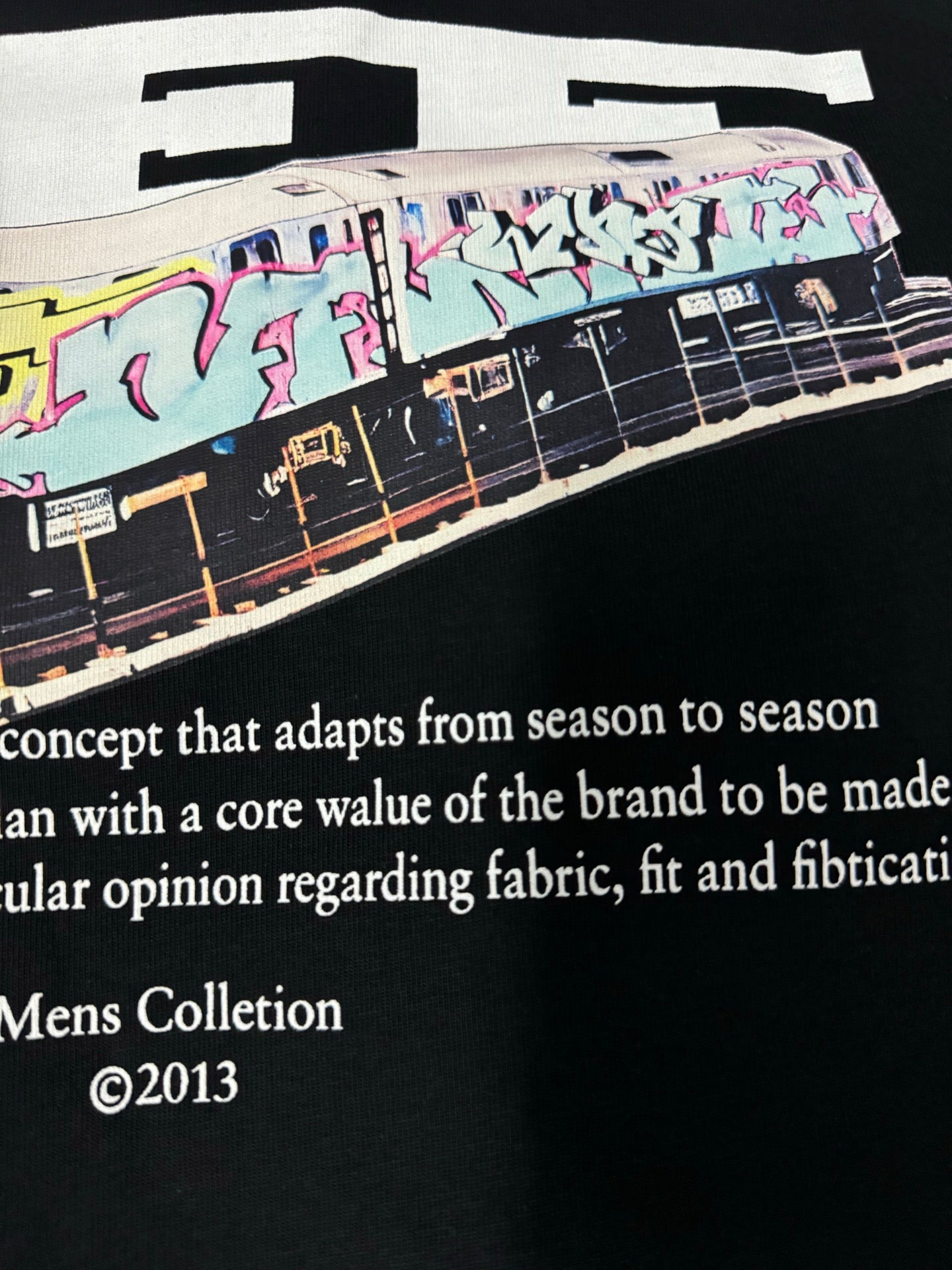 Black T-shirt close-up with bus artwork and “Mens Collection ©2013” text