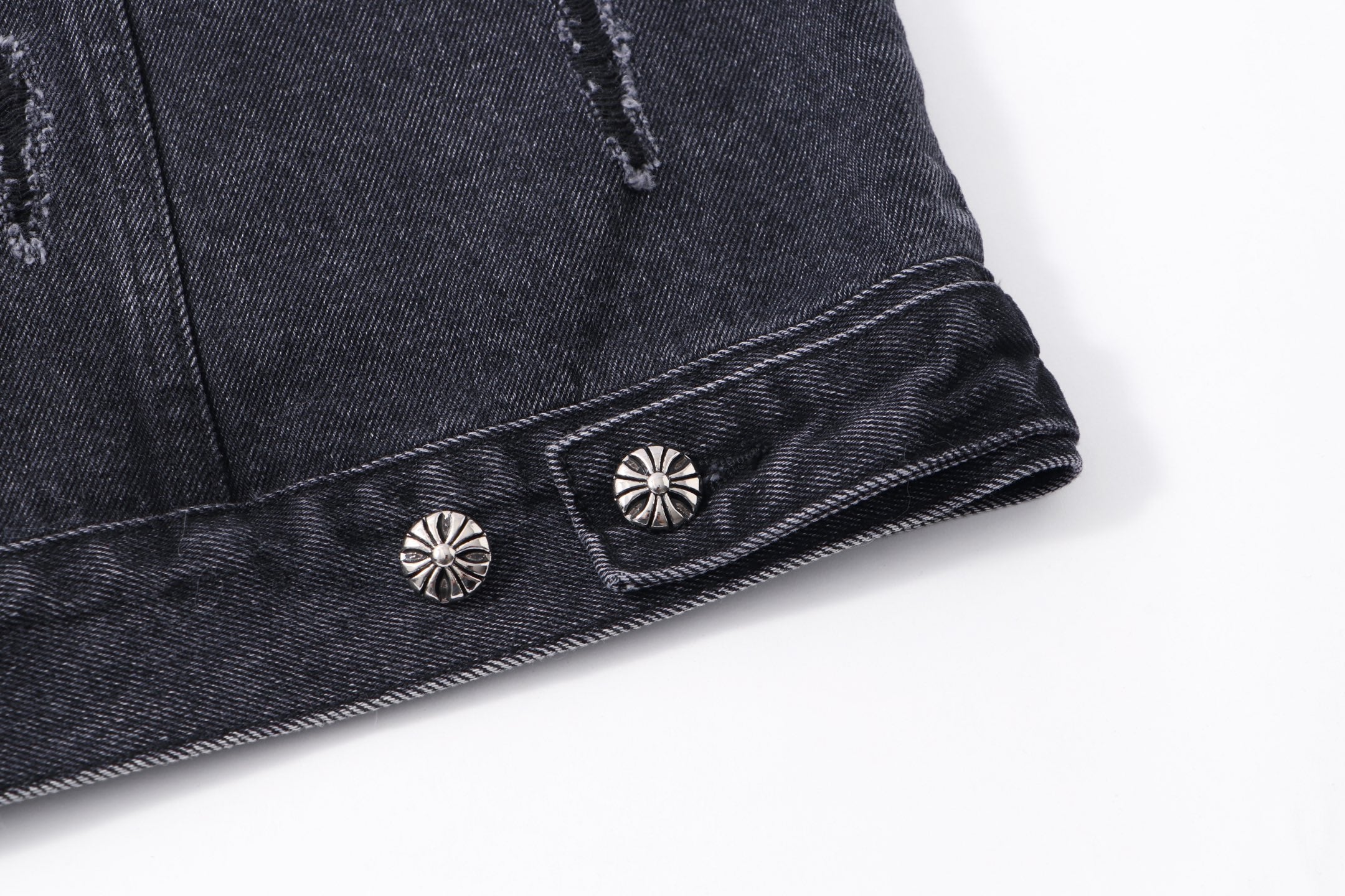 Dark denim jacket hem with decorative snap stud buttons and embroidered motifs