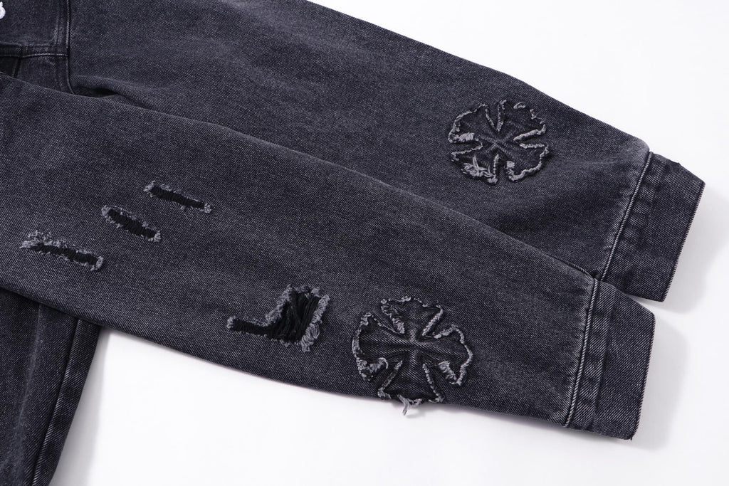 Dark denim jacket sleeve with embroidered star-like motifs near cuff