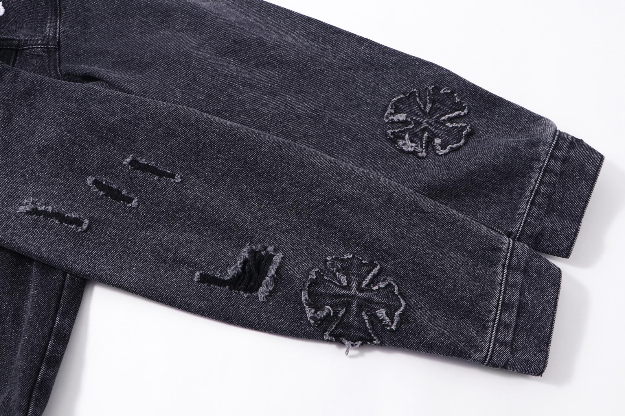 Dark denim jacket sleeve with embroidered star-like motifs near cuff