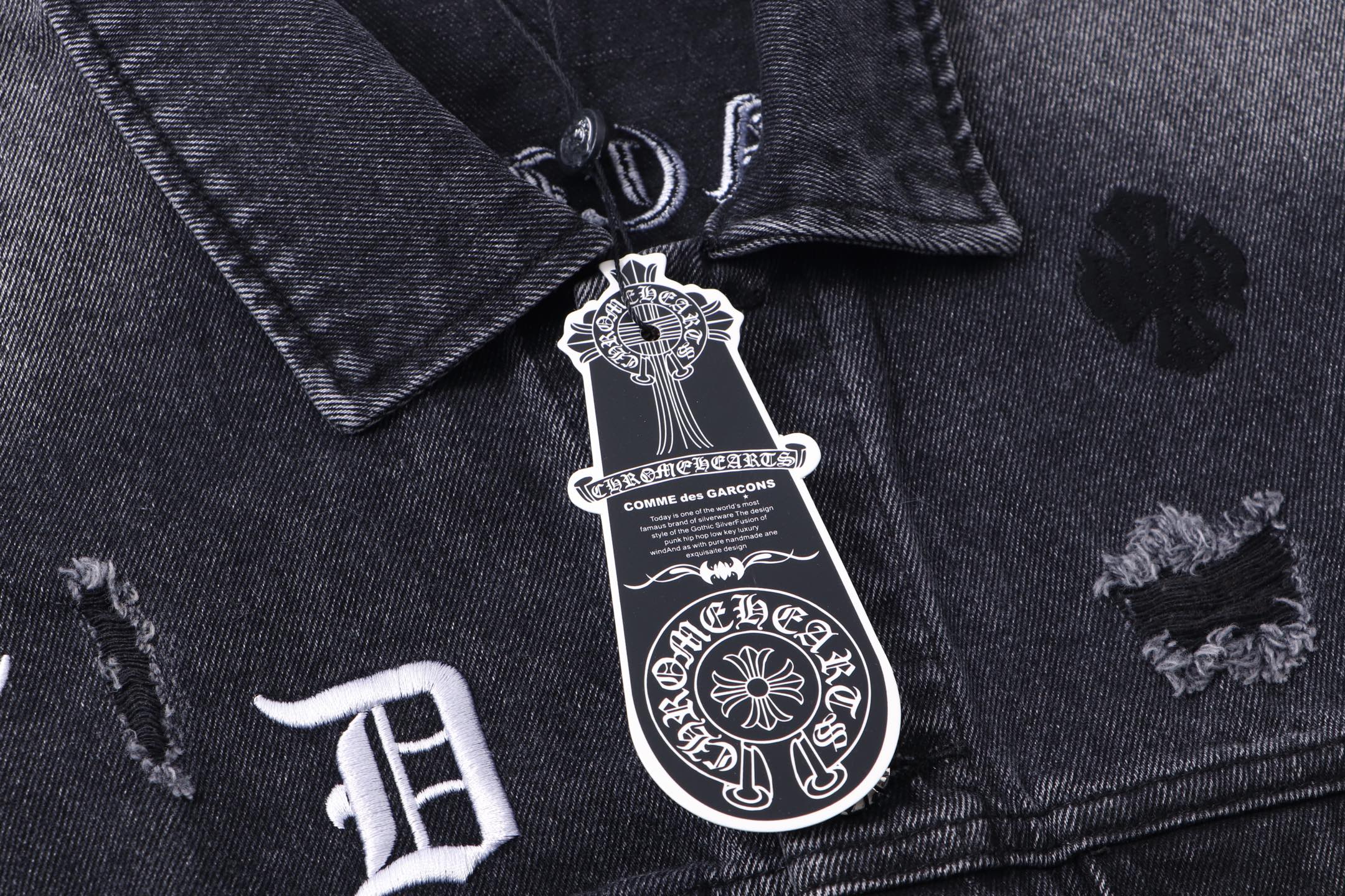Dark denim jacket front collar with engraved emblem patch and small embroidery