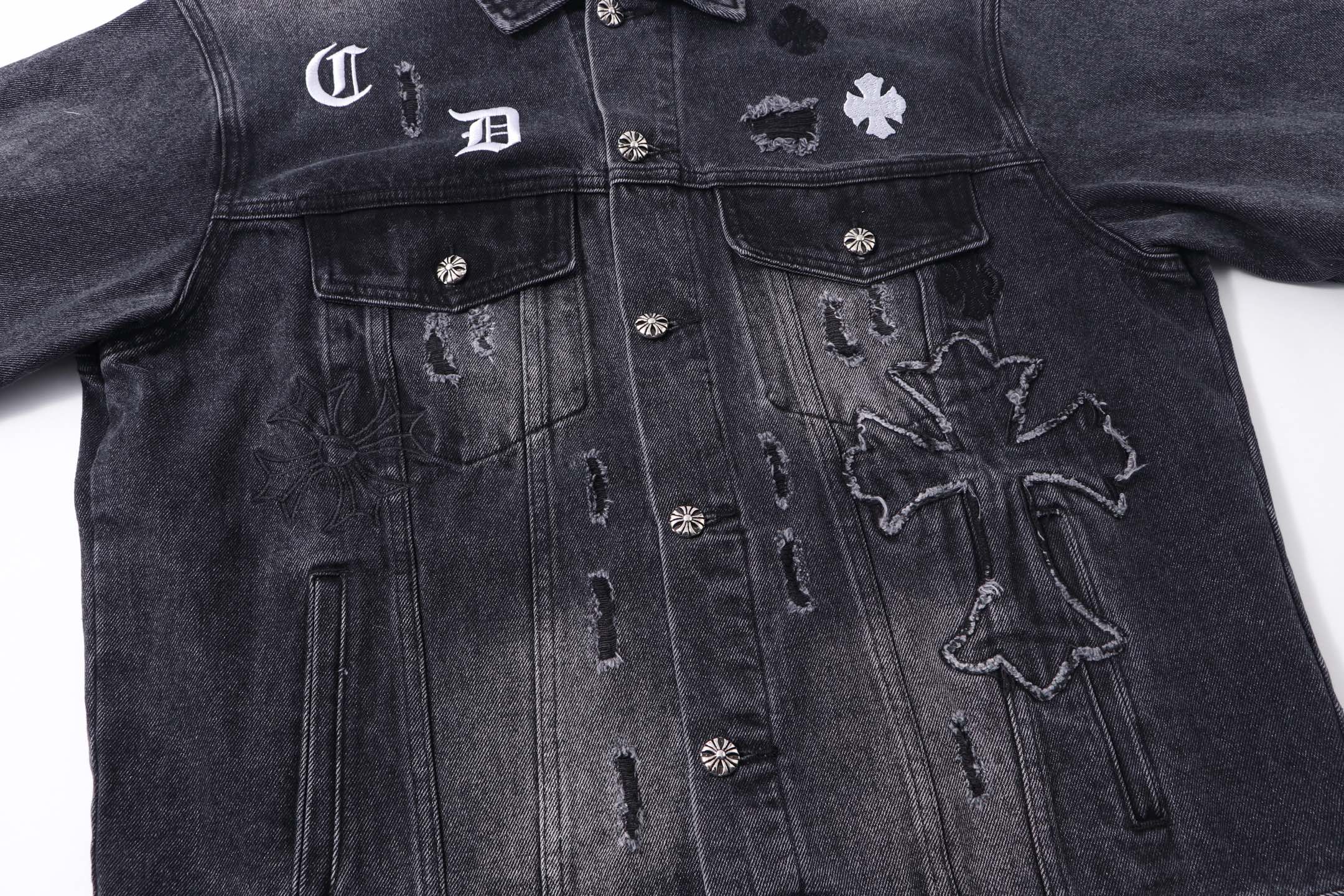 Dark denim jacket front with flap pockets and embroidered cross graphics