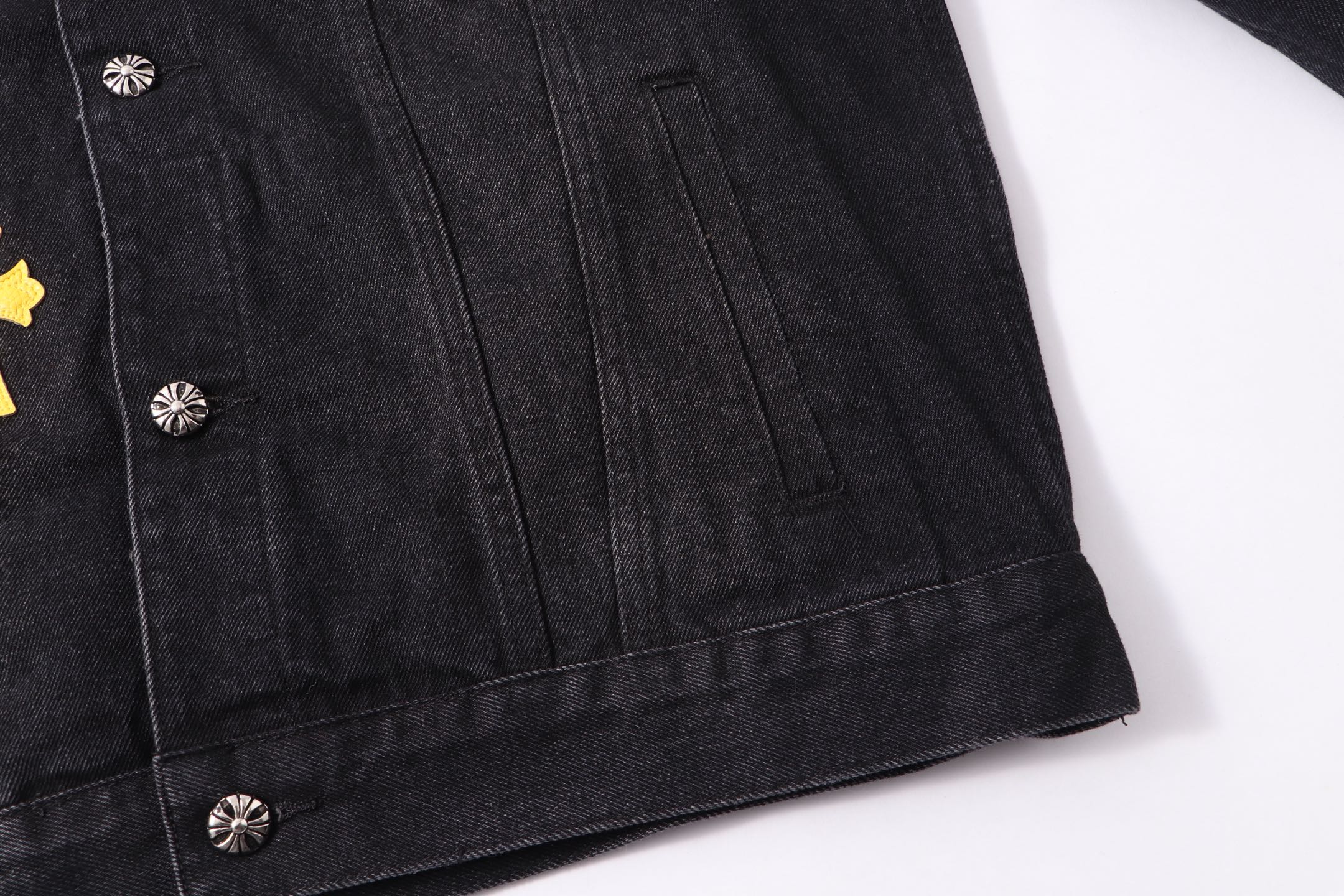 Black denim-style jacket hem with silver buttons and stitch detailing