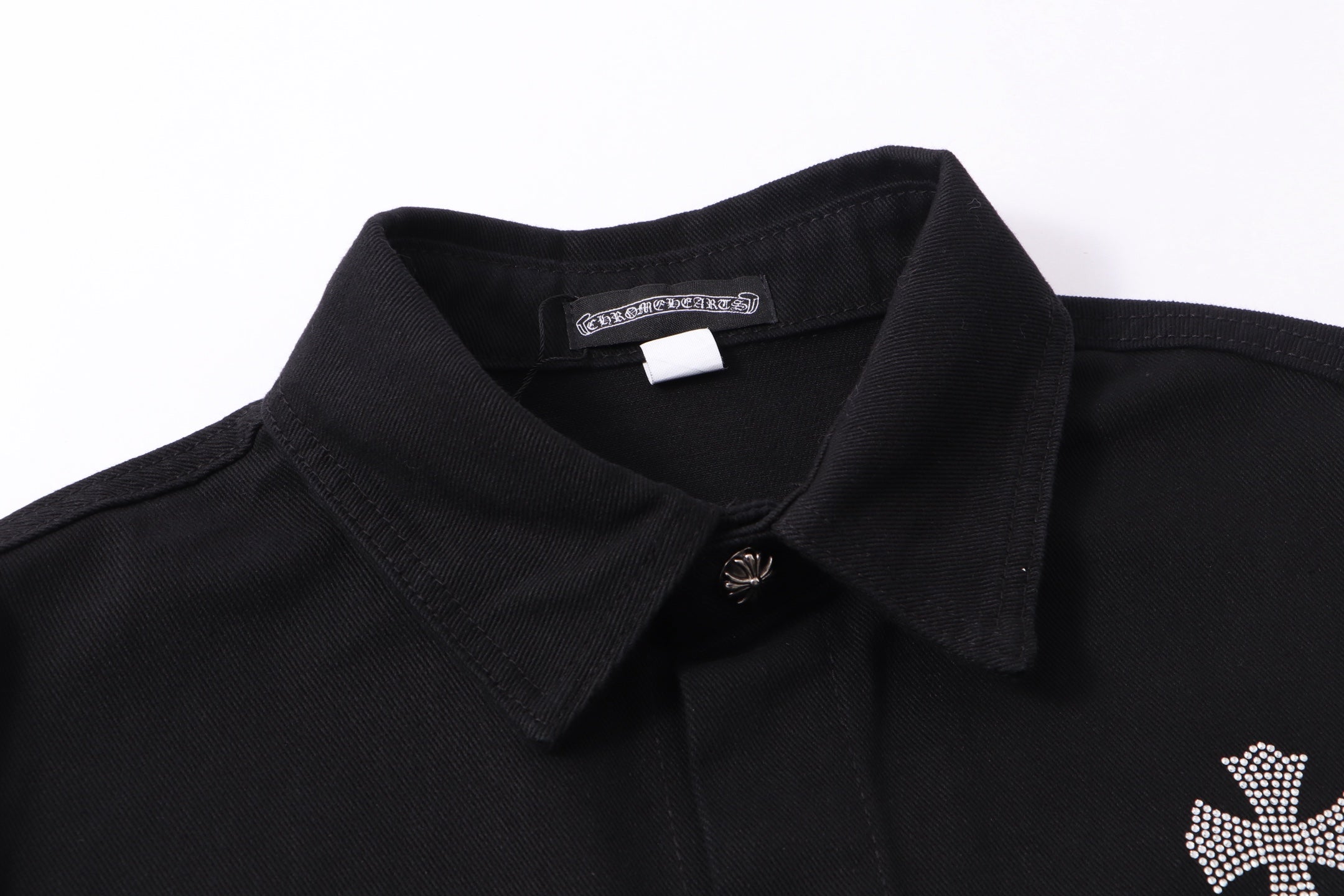 Black shirt jacket with pointed collar, button placket, and rhinestone logo detail