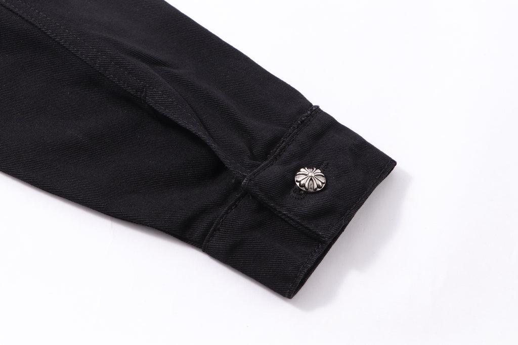 Black shirt sleeve cuff close-up with decorative button detail.