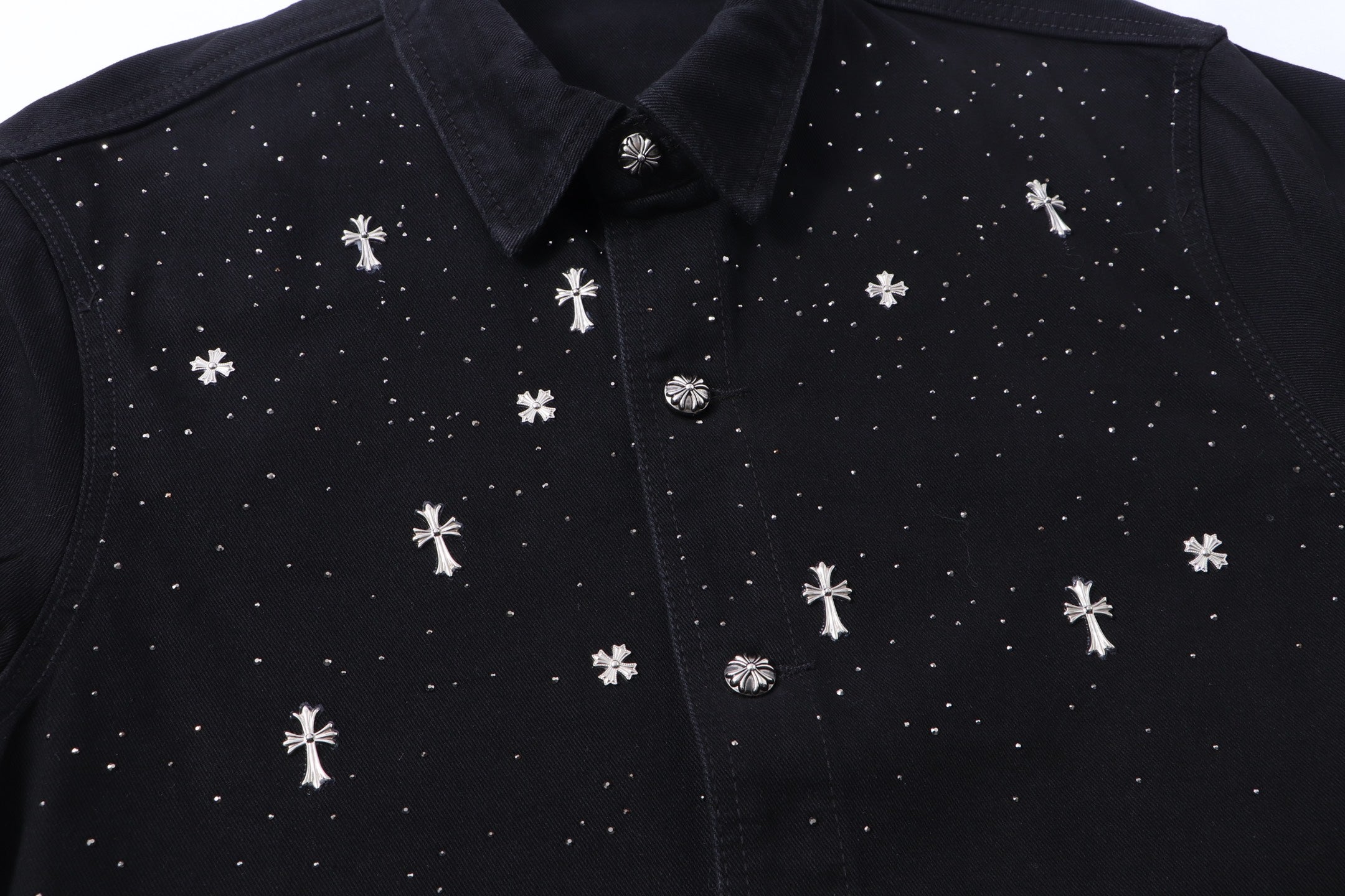 Black shirt front close-up with white cross motifs and button placket.