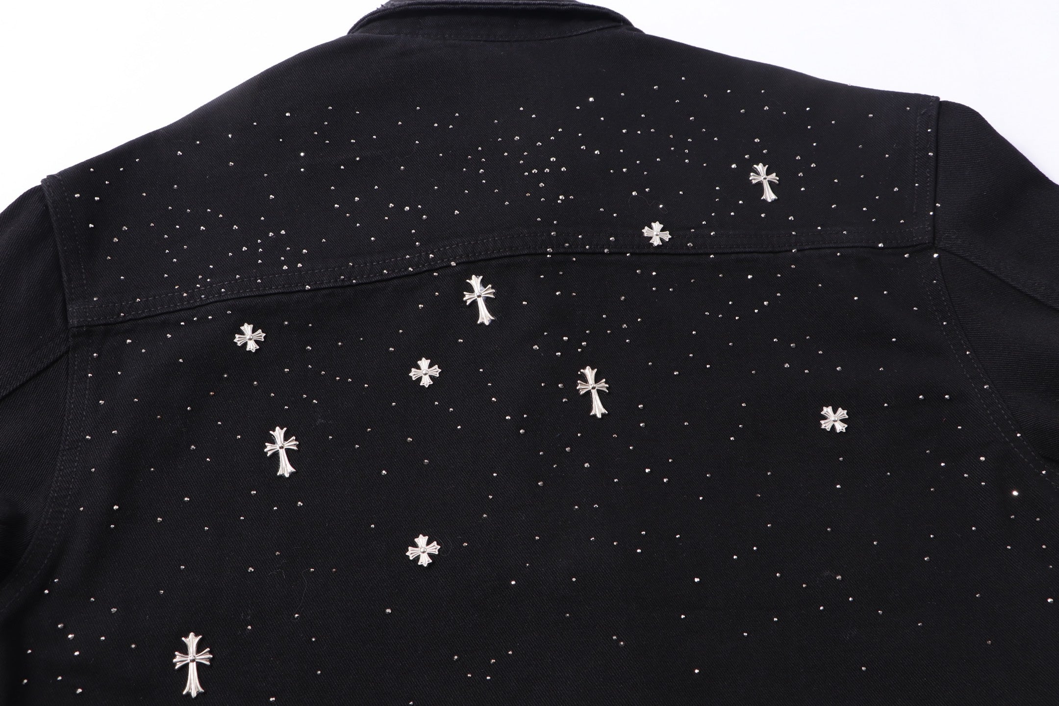 Back yoke close-up with white star and cross motifs across black shirt.