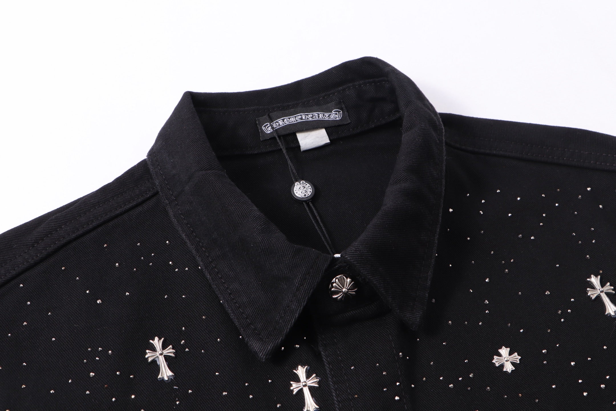 Black shirt neckline close-up with collar, front buttons, and white motif accents.