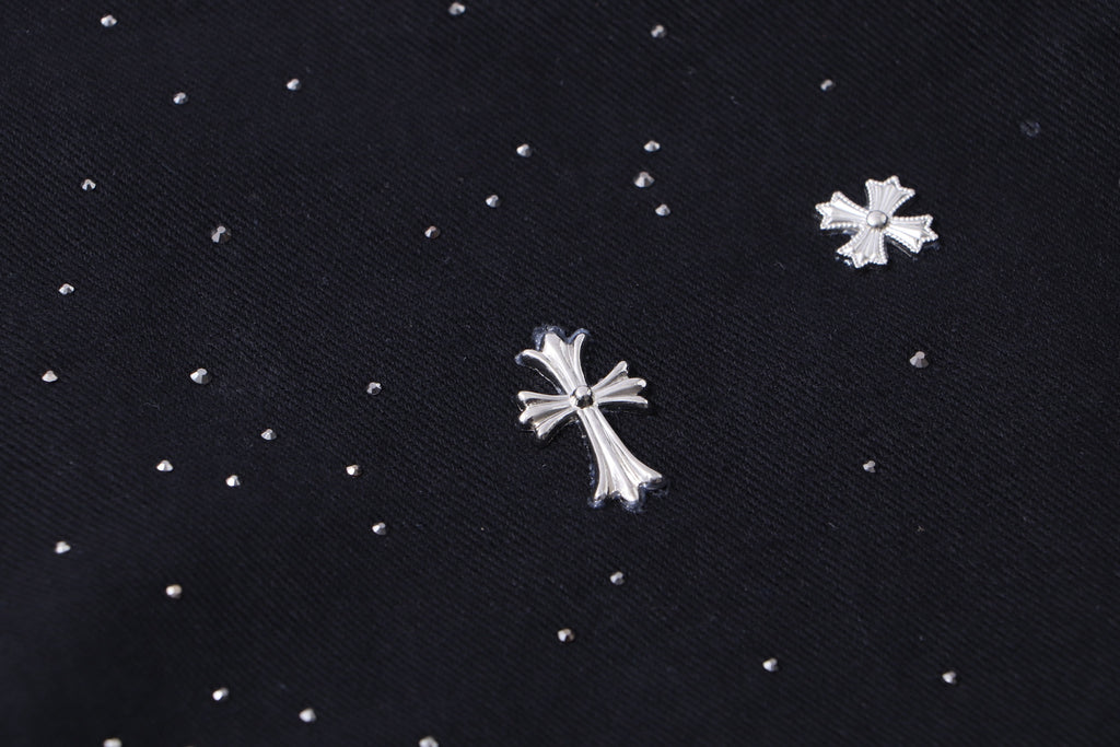 Close-up of black fabric with scattered white cross and star embellishments.