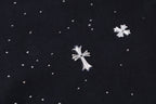 Close-up of black fabric with scattered white cross and star embellishments.