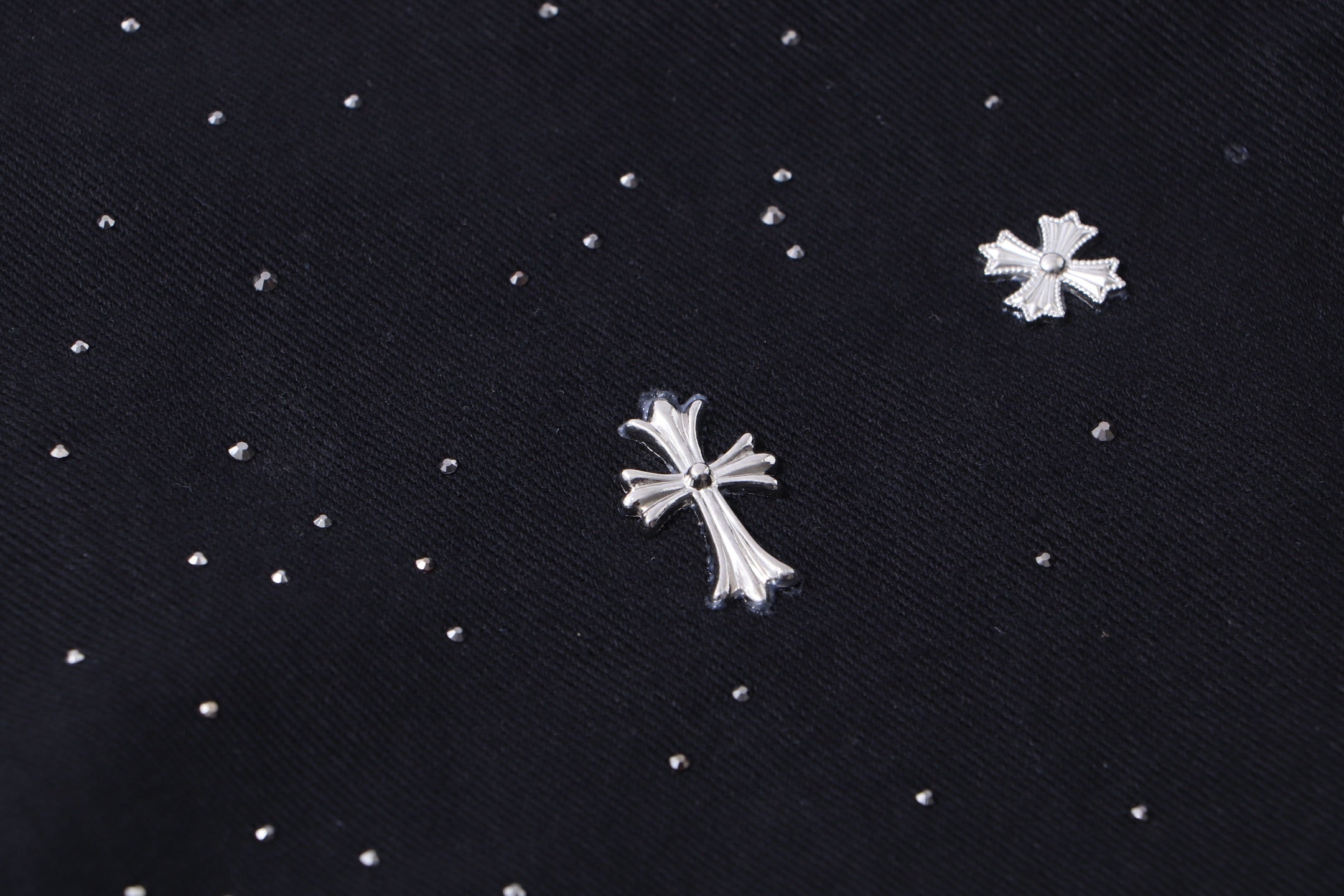 Close-up of black fabric with scattered white cross and star embellishments.