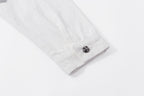 White jacket sleeve cuff with metal button and visible stitching detail