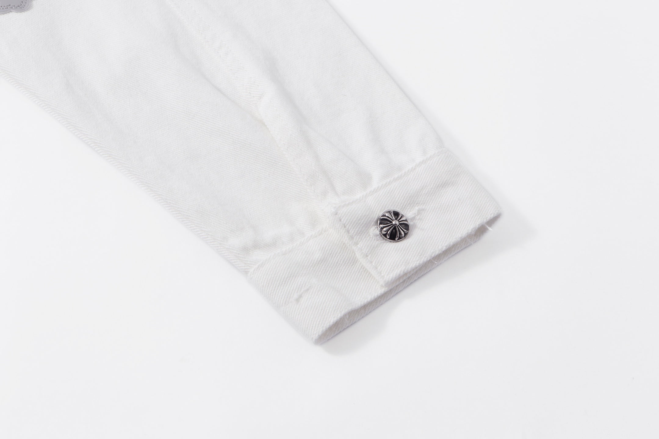 White jacket sleeve cuff with metal button and visible stitching detail