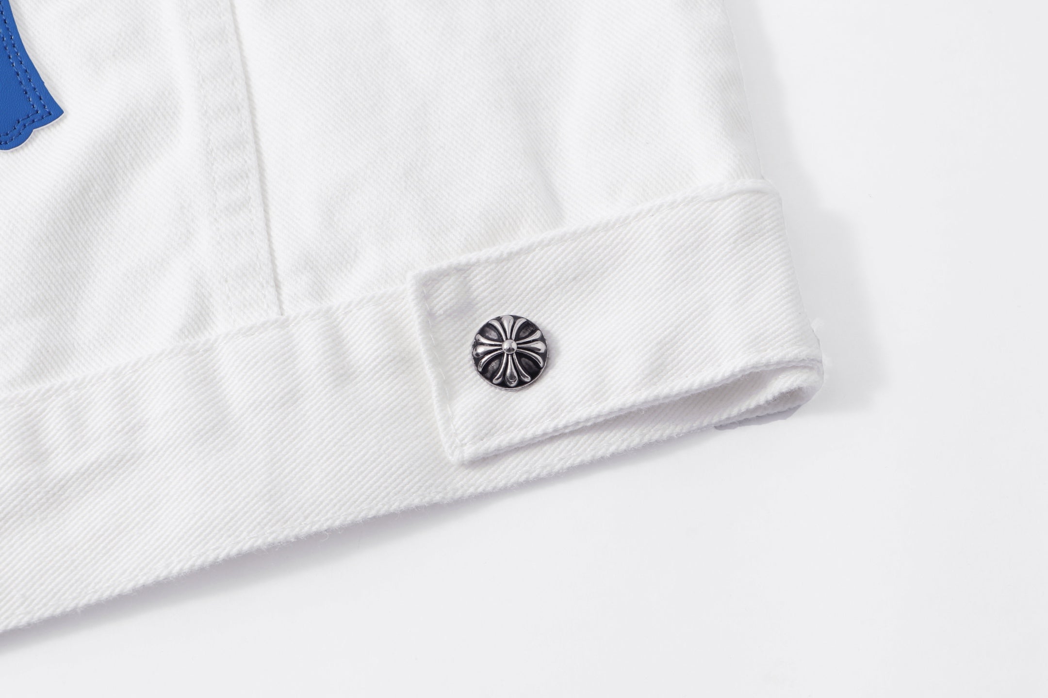 White jacket hem with small metal button and reinforced fabric stitching