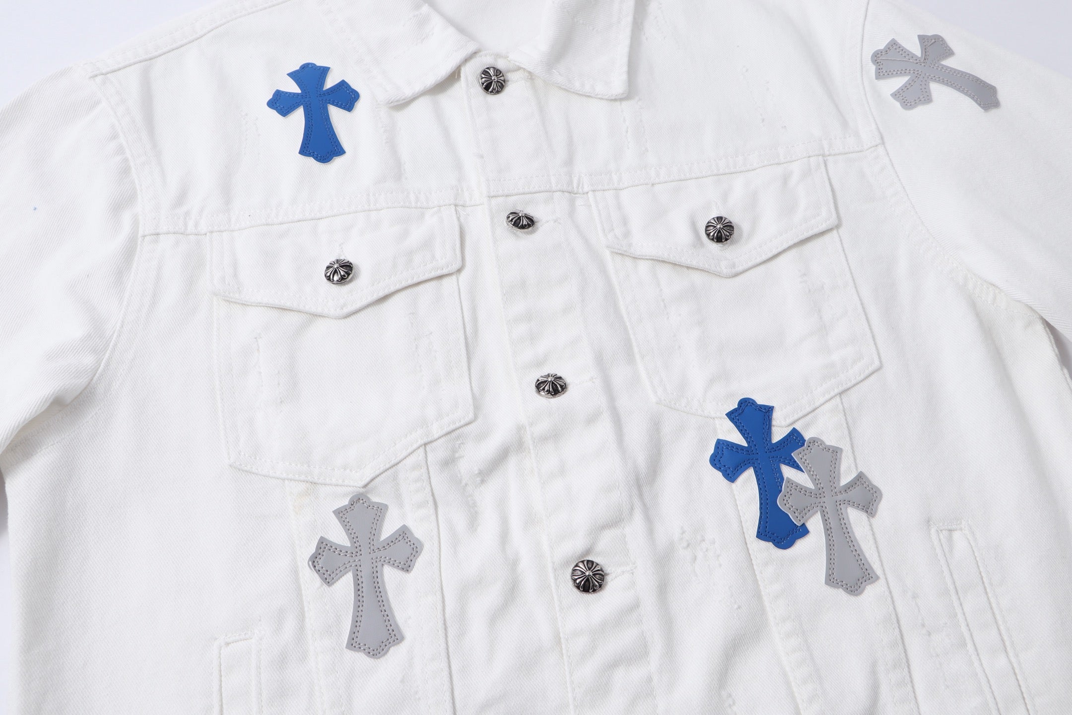 White long-sleeve jacket with multiple blue and gray cross patches and front button closures