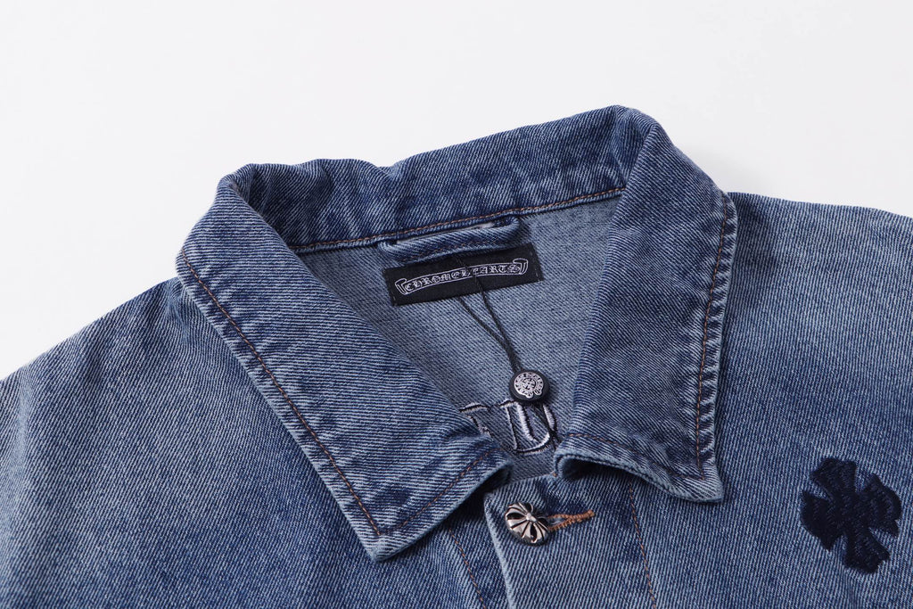 Blue denim jacket collar close-up with button and embroidered dark patch