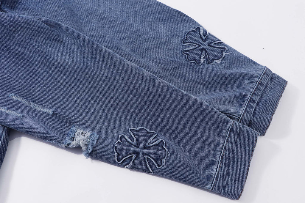 Blue denim jacket sleeves with embroidered cross appliques and distressed cuffs