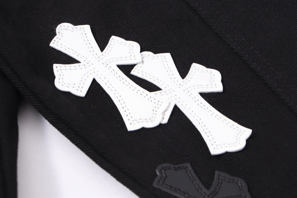 Black denim jacket sleeve detail with large white cross applique and stitched edges