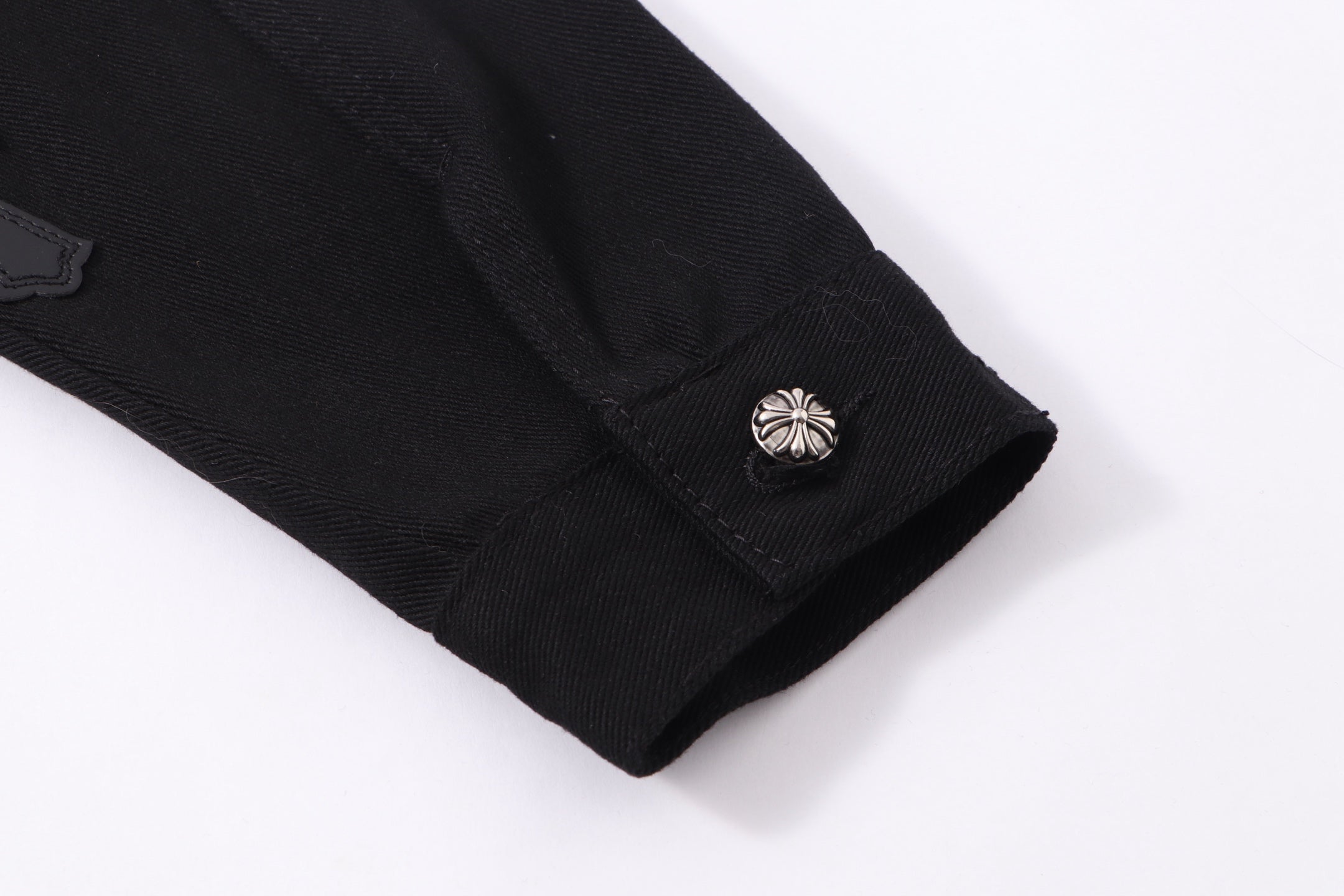 Black denim jacket sleeve hem with metallic snap button