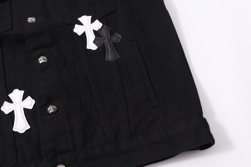 Black denim jacket lower front detail with white cross patch and snap buttons