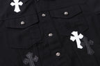 Black denim jacket front close-up with flap pockets, snaps, and cross appliques