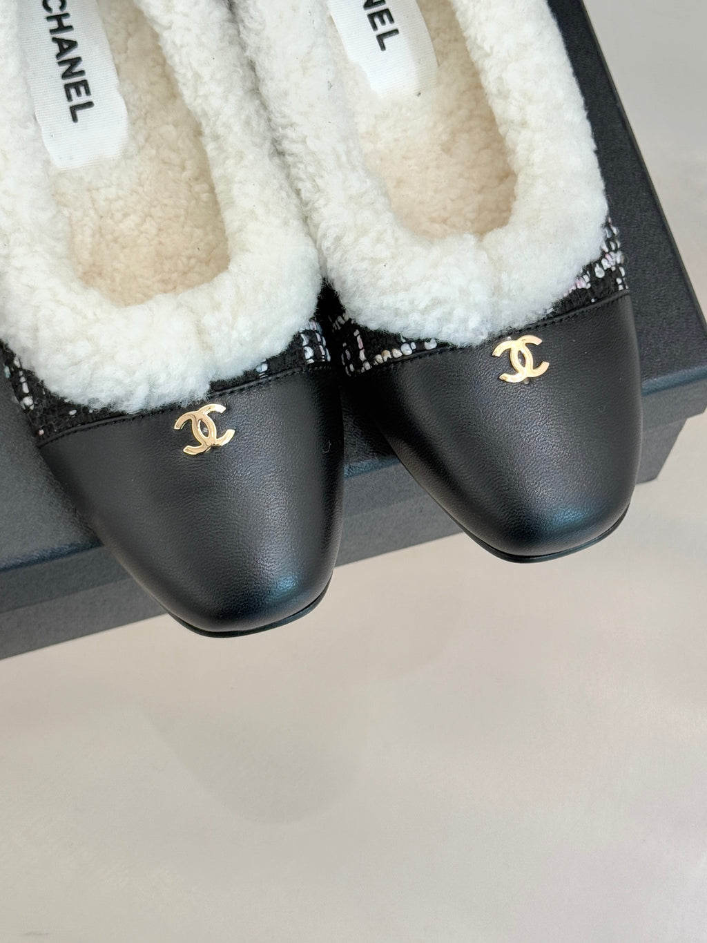 Women’s Chanel loafers close-up, white sherpa lining and black leather with Chanel emblem