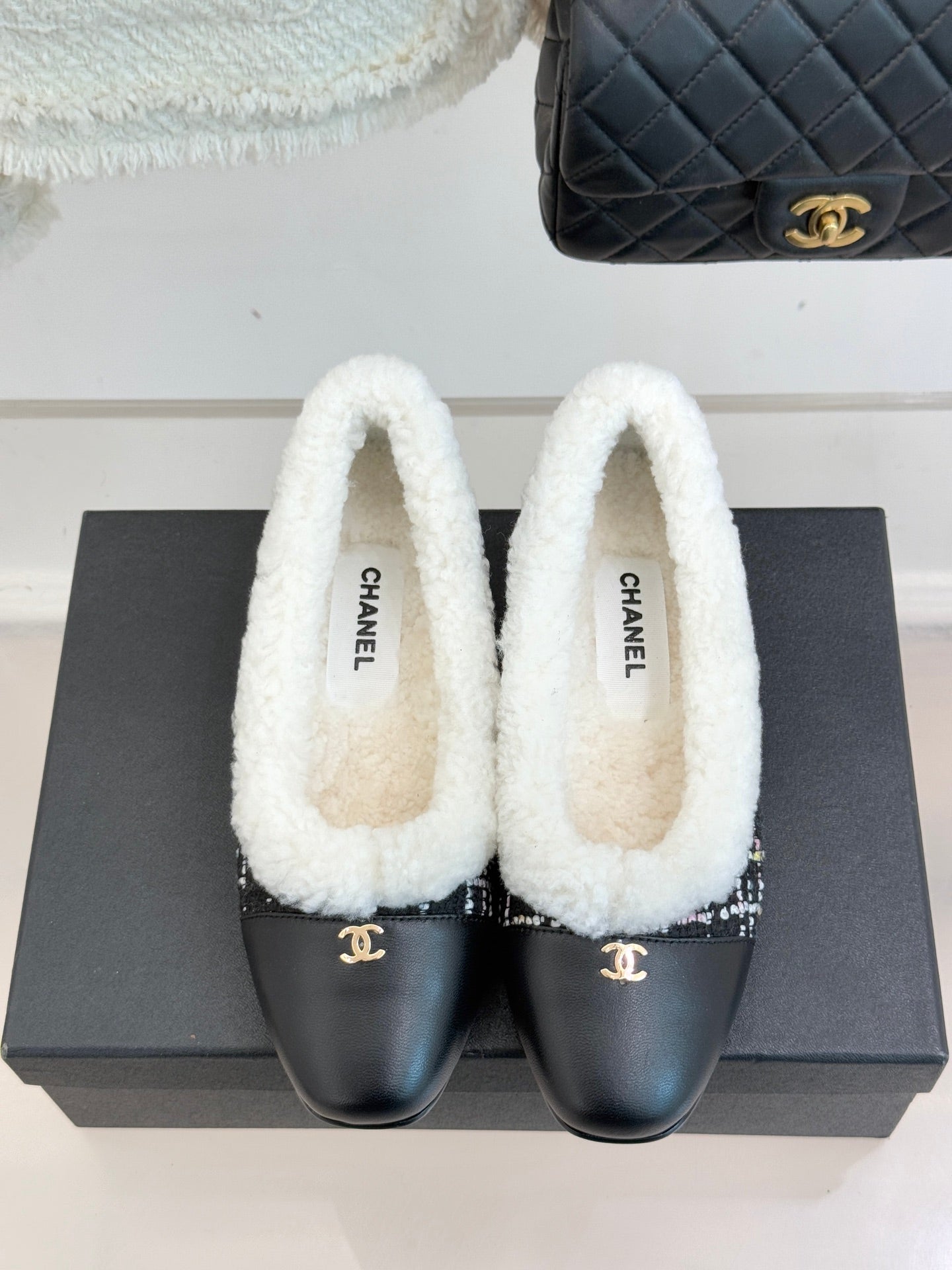 Women’s Chanel loafers with white sherpa collar and black leather toe with Chanel logo