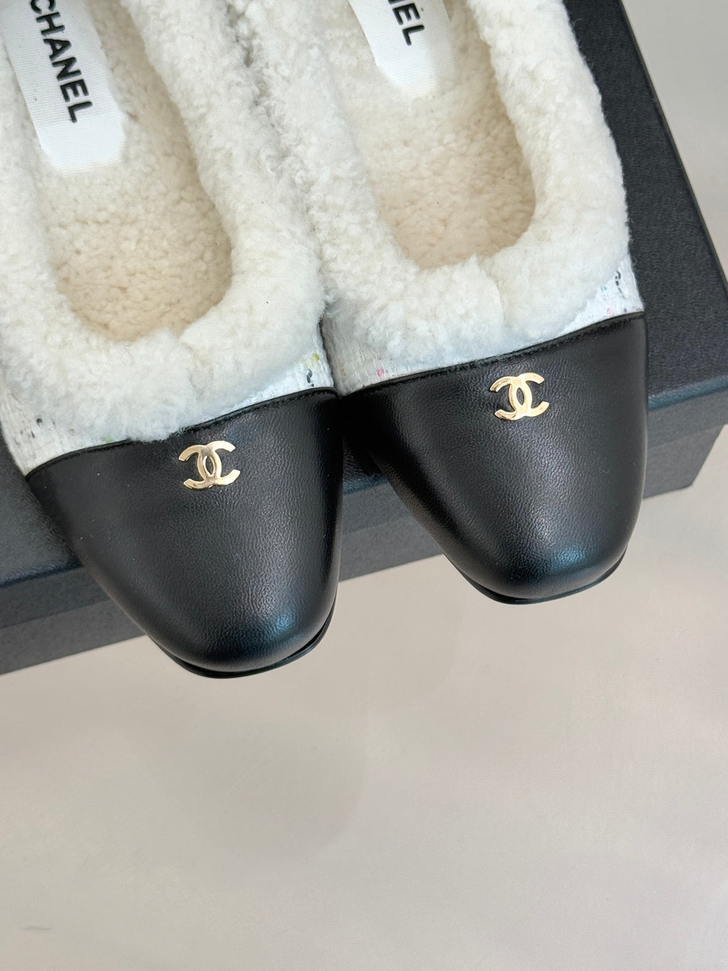 Women's Chanel flats with black leather fronts and white fleece interior lining