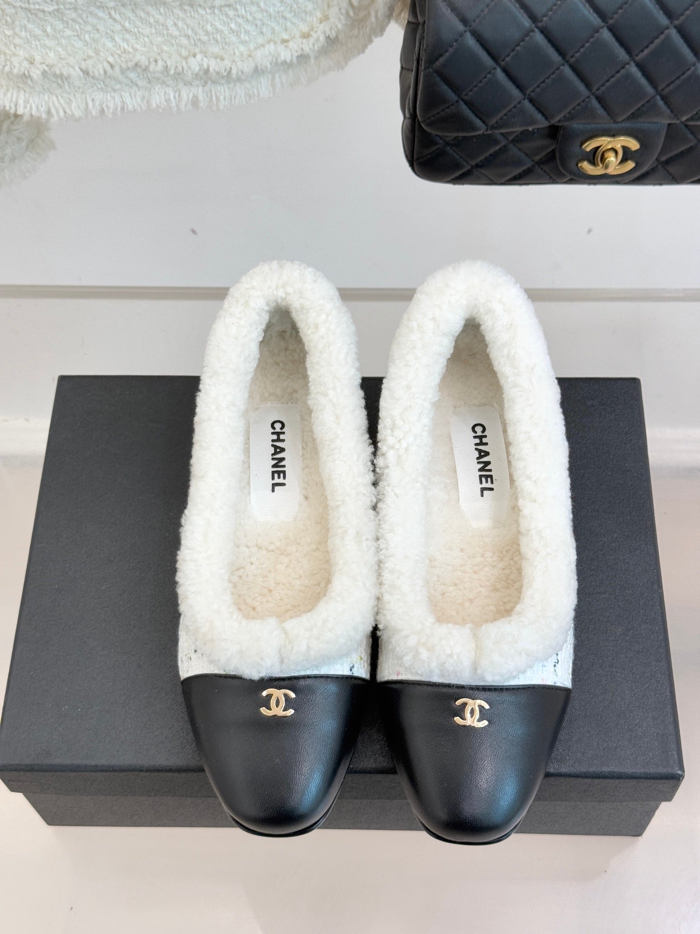Women's Chanel shearling mules with white fleece tops and black leather toe caps