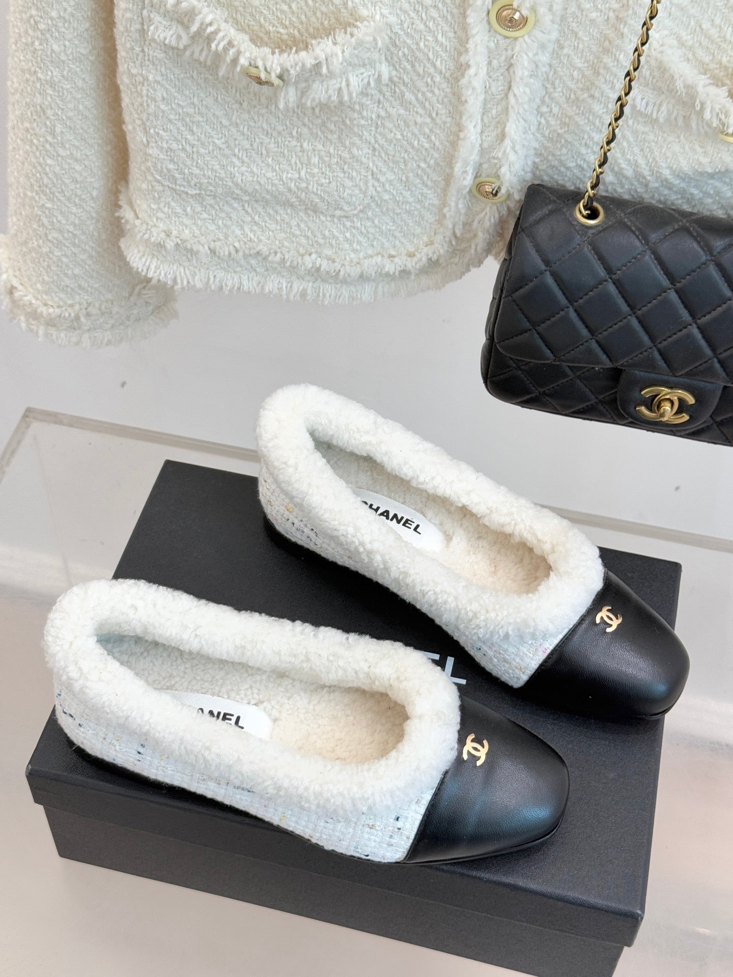 Pair of women's Chanel flats with black toes and light blue shearling lining