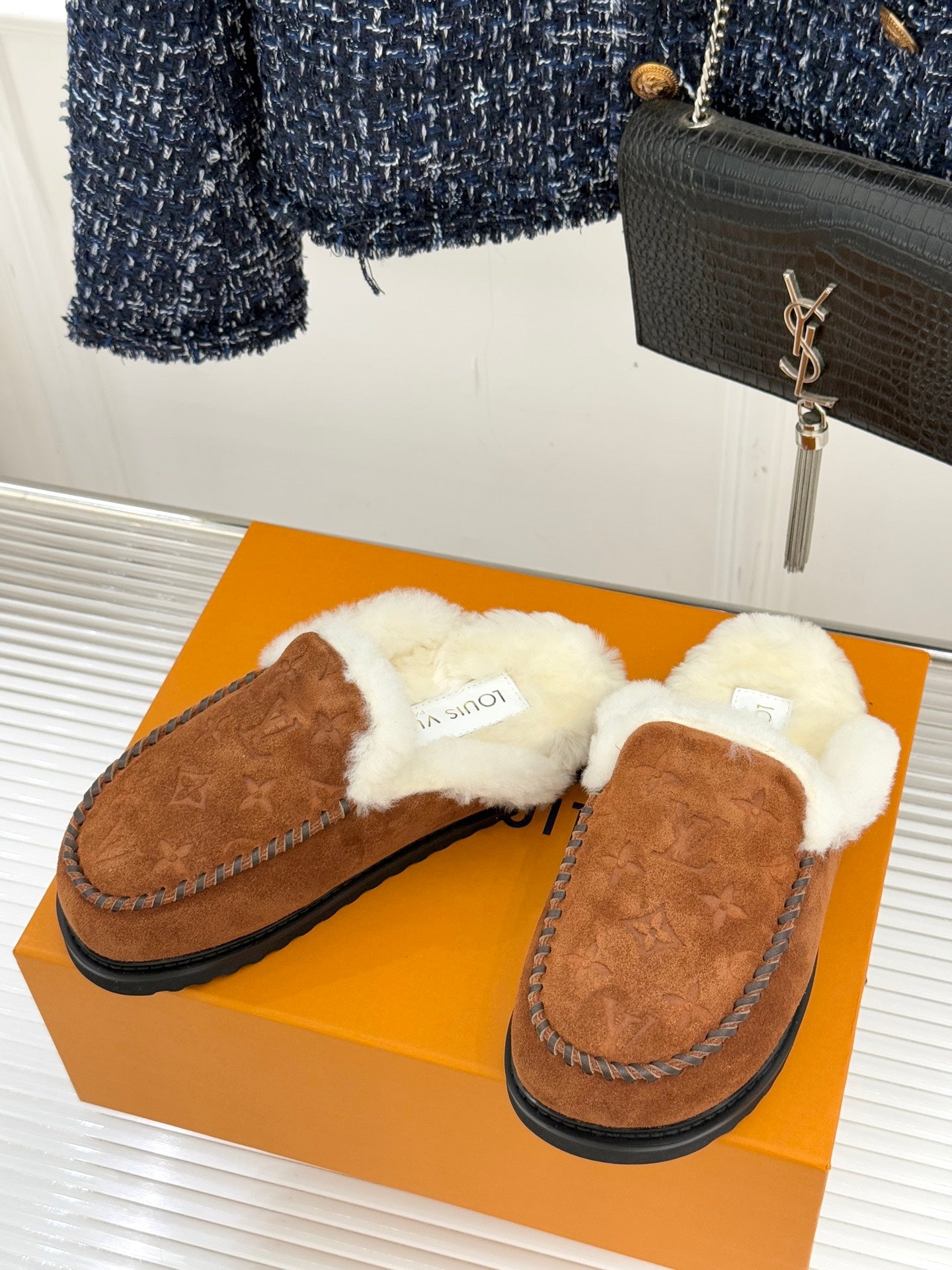 Pair of brown suede shearling loafers with plush white lining and stitched edges