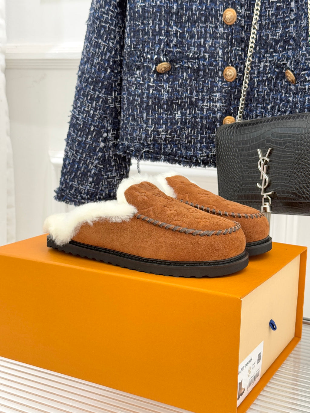Brown suede loafer with white shearling trim and black rubber sole