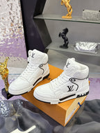 Pair of white Louis Vuitton high-top sneakers with LV logo and black rubber trim