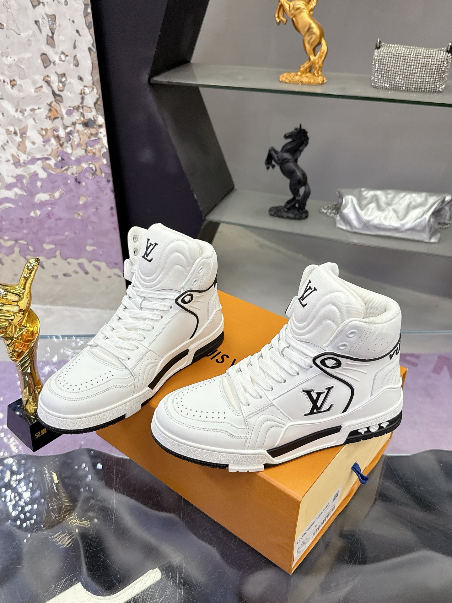 Pair of white Louis Vuitton high-top sneakers with LV logo and black rubber trim