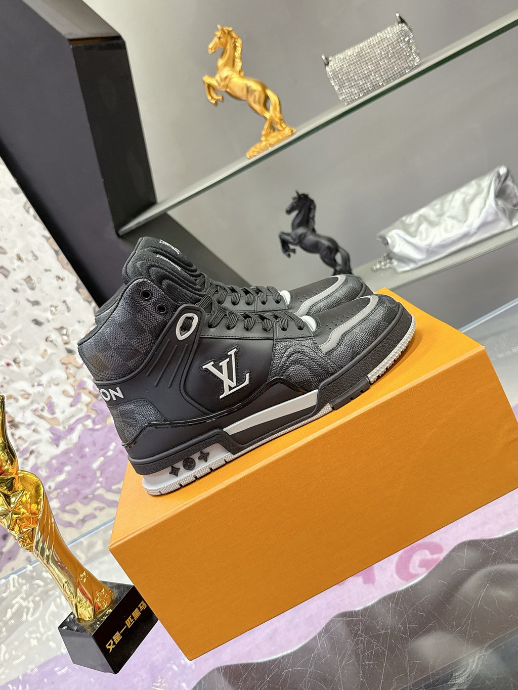 Louis Vuitton high-top sneakers on orange box, dark gray/black with LV side logo and laces