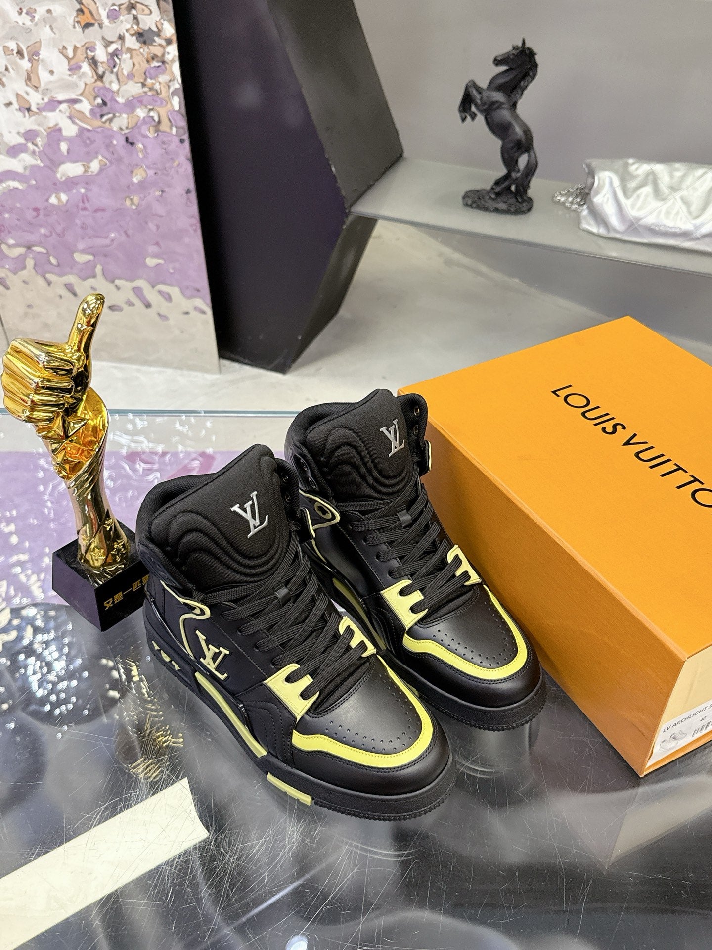 Black high-top sneakers on orange box with neon yellow trim and logo detail
