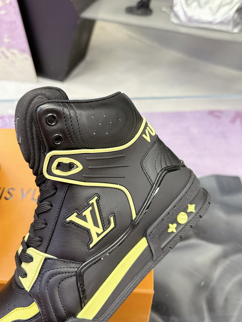 Black high-top sneakers close-up showing neon yellow lace loops and side logo