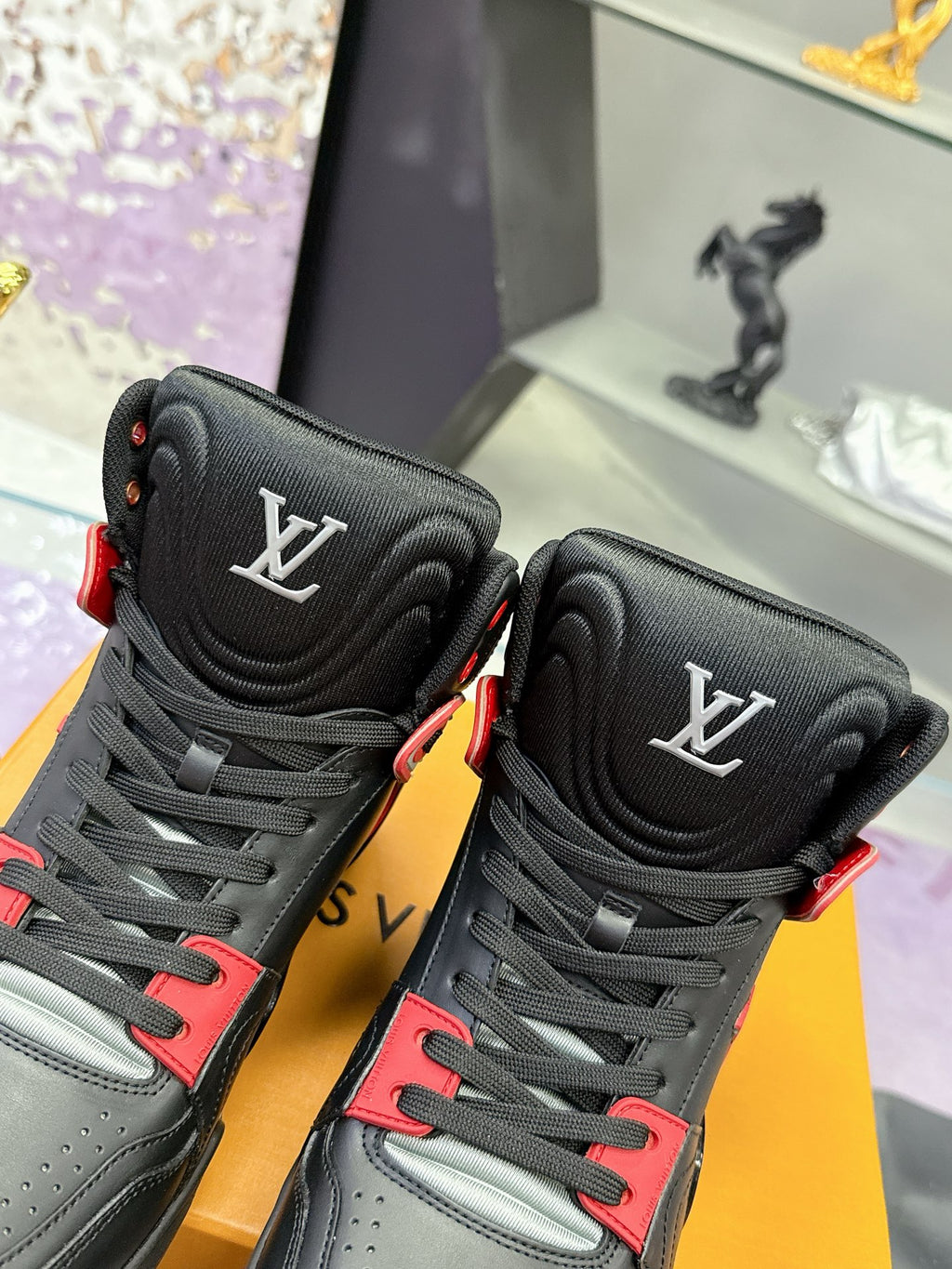 Louis Vuitton high-top sneakers close-up, black uppers with red trim and LV logos