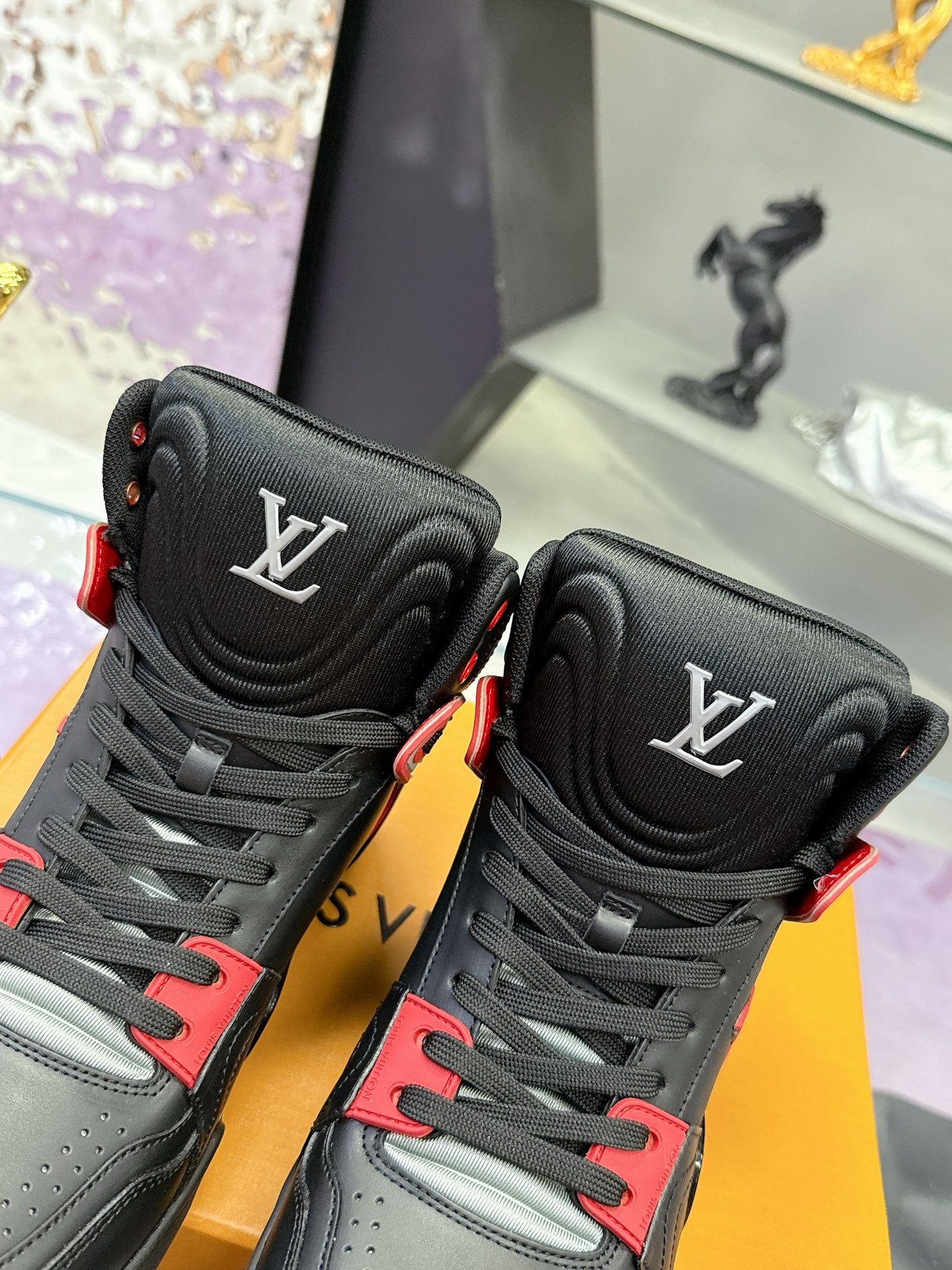 Louis Vuitton high-top sneakers close-up, black uppers with red trim and LV logos