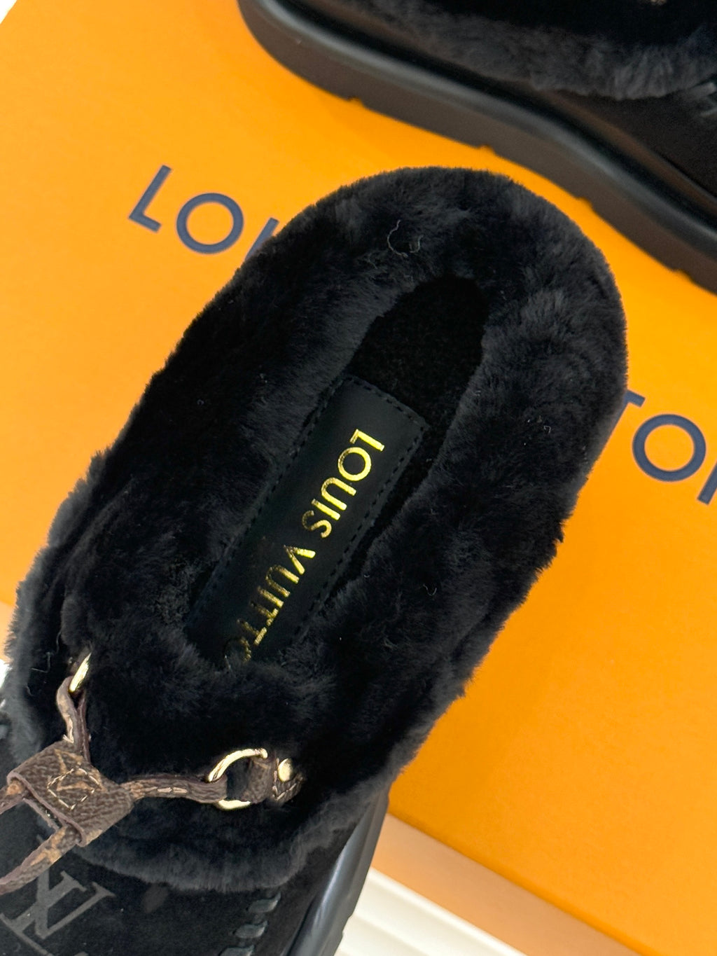 Black shearling loafer with monogram trim and gold "Louis Vuitton" text on insole