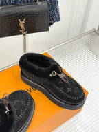 Black shearling loafers with monogram detailing and gold-tone buckle, angled side view