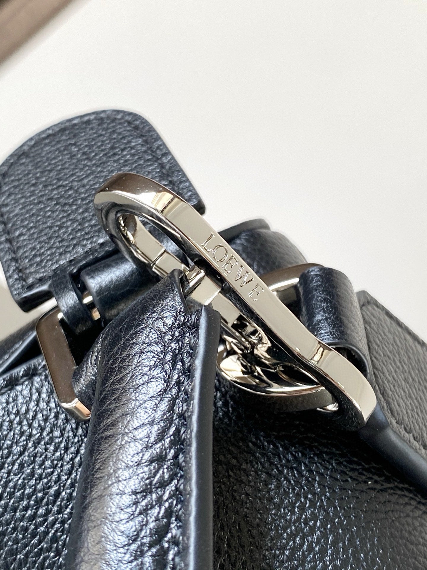 Loewe men's bag hardware close-up on textured dark blue leather with metal clasp