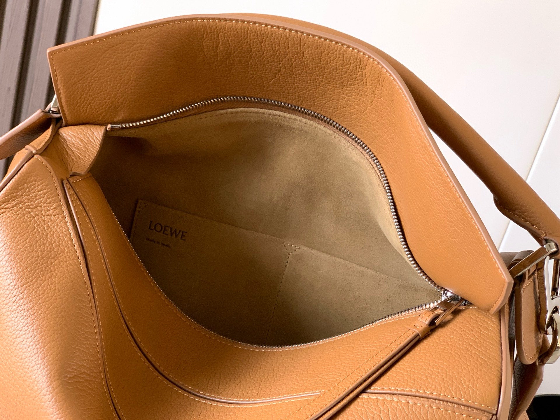 Open tan leather bag interior with fabric lining and zippered top closure.