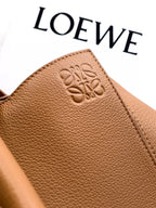Tan leather bag panel with embossed logo and textured grain finish.