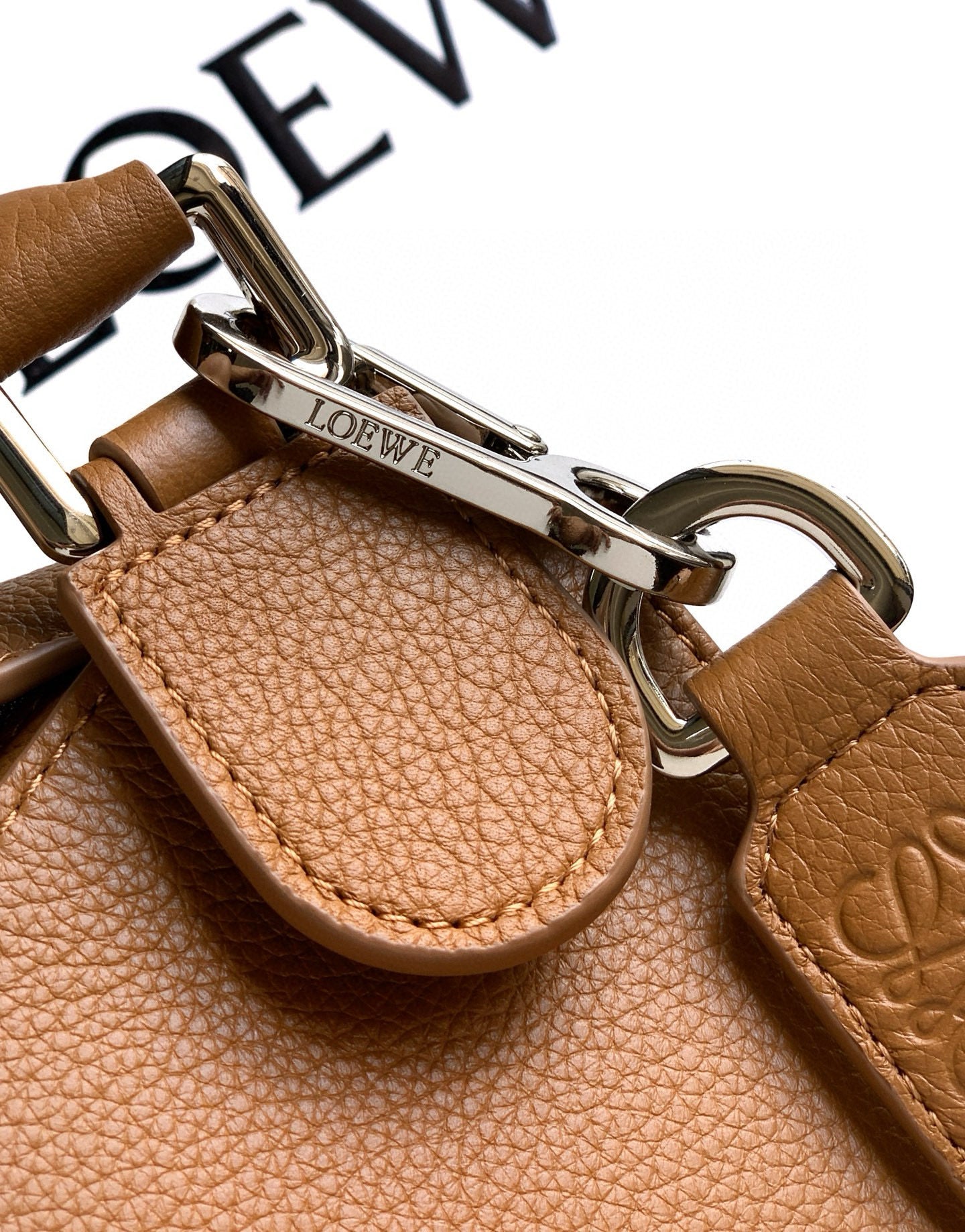Tan leather key-holder tab with metal clasp and LOEWE logo detail.