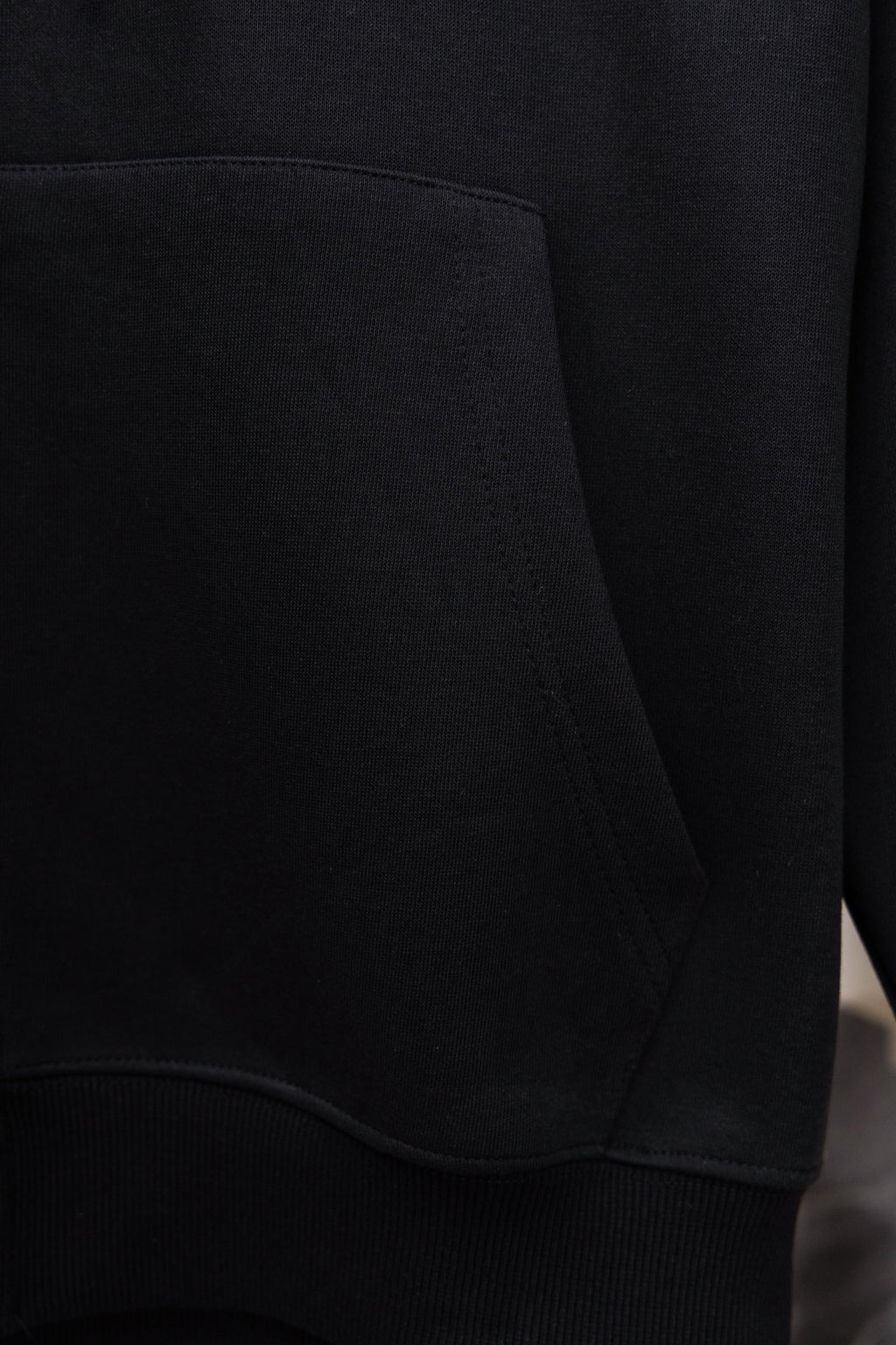 Black hoodie front pocket with curved side seam and ribbed cuff trim